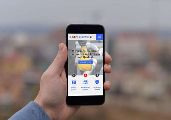 Smartphone vor unscharfem Hintergrund auf dem die Website des Unternehmens ERS-Systeme aus Weißwasser angezeigt wird
